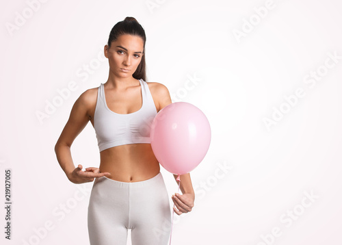 Woman holding a balloon, feeling bloated concept  