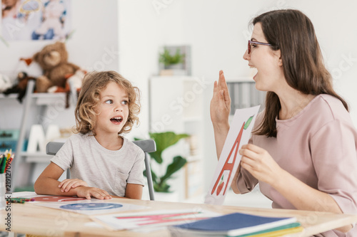 Photo Speech therapist teaching letter a young boy in a classroom