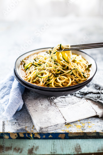 Asian style noodle soup with glass noodles and zoodles in red curry broth photo