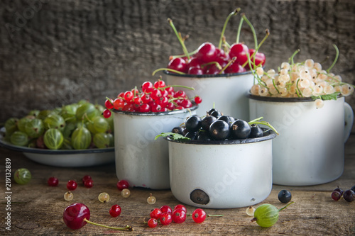 Various fresh summer berries in metal bawl on wooden background. photo