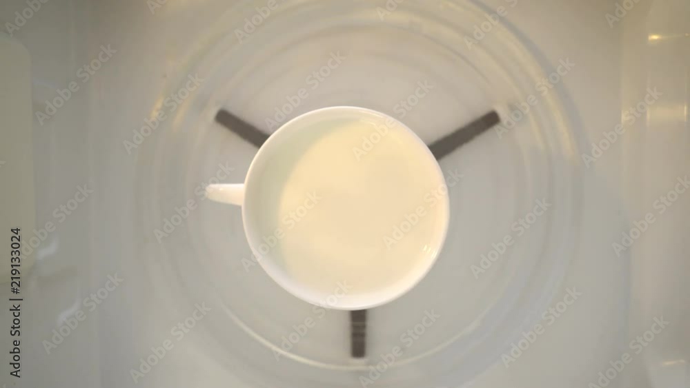 Heating milk in microwave. Mug of milk turning around in microwave top