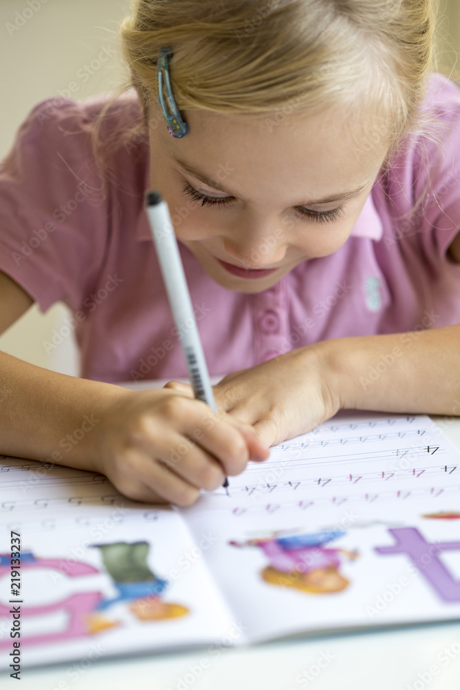 Smiling little girl writing numbers in exercise book Smiling little girl writing numbers in exercise book