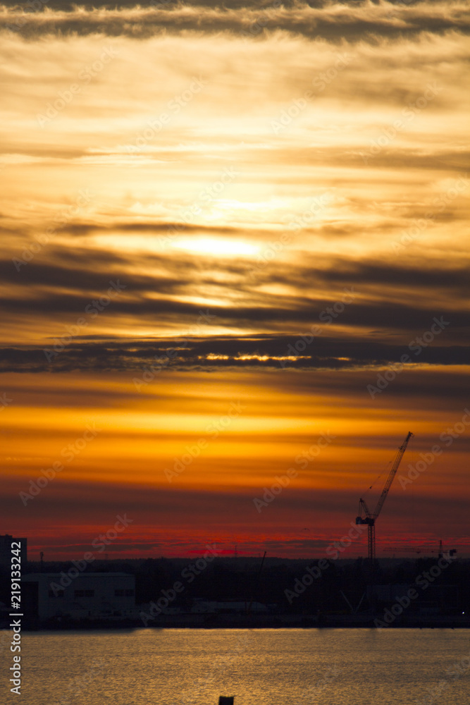 Sunset over the city. Tower crane. Industrial landscape. Twilight colored sky. Bright sunset over the horizon