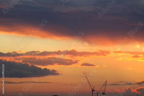 Sunset over the city. Tower crane. Industrial landscape. Twilight colored sky. Bright sunset over the horizon