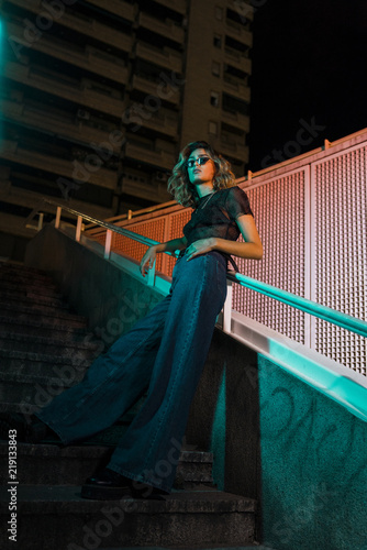 Stylish young woman at night in the city, wearing sunglasses