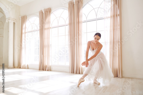 Ballerina dancing in a studio on white background window.