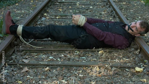 Tied Up Businessman Trying to Free Himself on a Rail Tracks