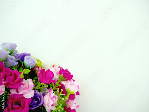 The plastic roses are on the white paper for writing note  which is on the table.