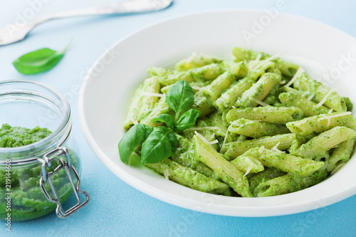 Traditional italian plate of pasta with pesto sauce decorated basil leaves and cheese.