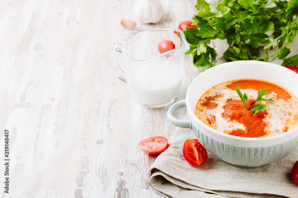 Bowl of homemade tomato soup with cream and parsley on wooden table. Copy spase for your text Bowl of homemade tomato soup with cream and parsley on wooden table. Copy spase for your text