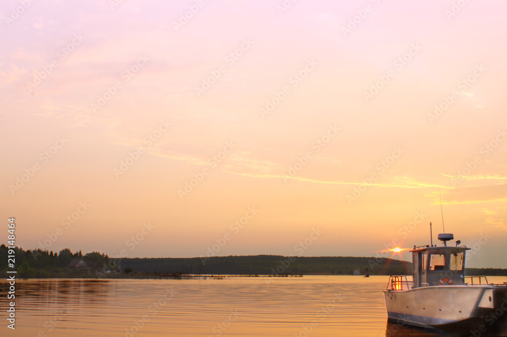 Lone Grey Silver Boat at Dock Mooring Harbor With Golden Orange Pink Beautiful Twilight Sunrise Dawn Morning Daybreak Sky Background on Still Dark Calm Lake Ocean Water