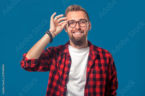 Emotional and people concept: young bearded man in checkered shirt. Hipster style. The guy adjusts his glasses © nazarovsergey