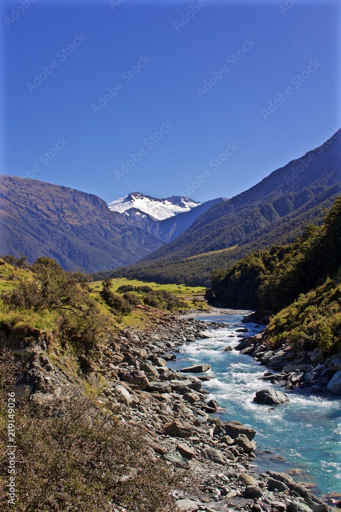 A Blue River Flows Down the Valley Through New Zealand from a Snow Capped Mountain