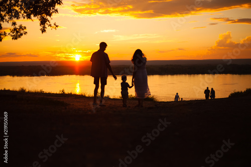 family, silhouettes of mom and dad on a background of beautiful sky, sunset, family at sunset