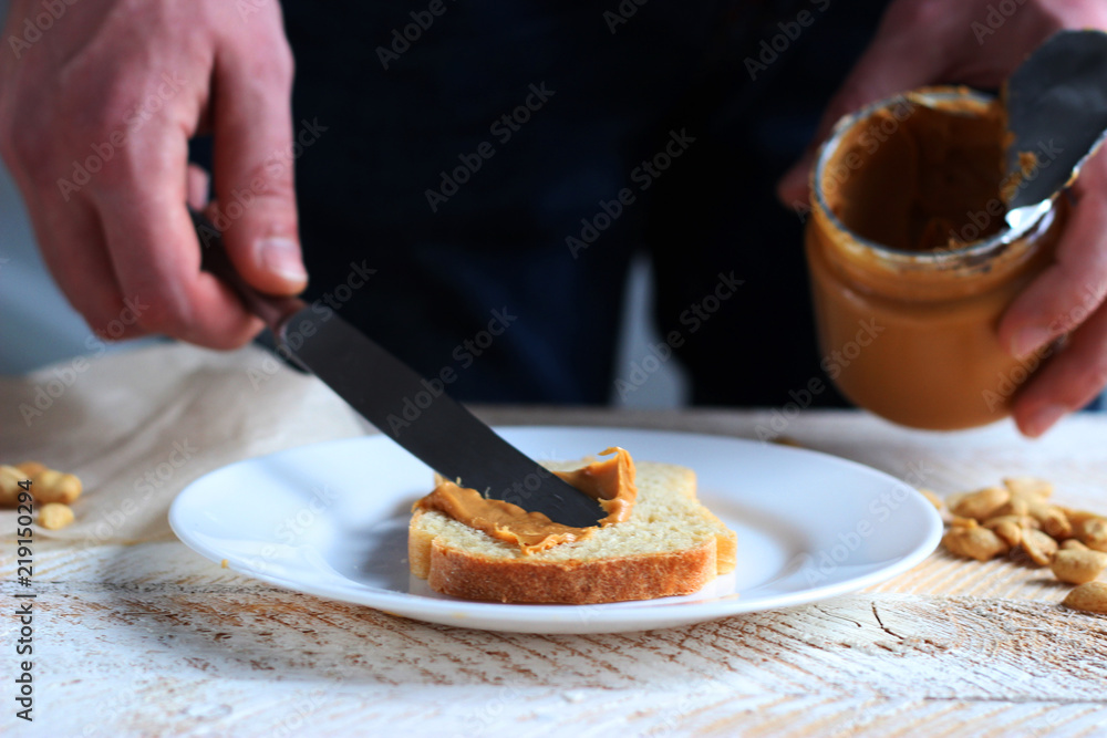 toasted white bread smeared peanut butter on a white plate on a light background