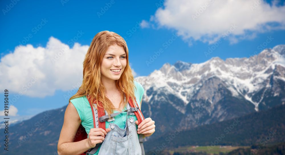 adventure, travel, tourism, hike and people concept - smiling young woman with backpack over alps mountains background