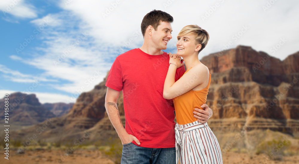 travel, tourism and summer holidays concept - happy smiling couple hugging over grand canyon national park background travel, tourism and summer holidays concept - happy smiling couple hugging over grand canyon national park background
