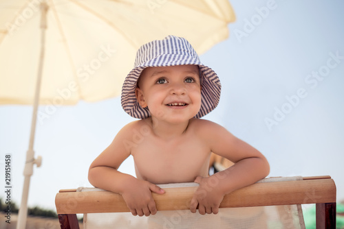 Photography Smiling boy sitting under a beach umbrella