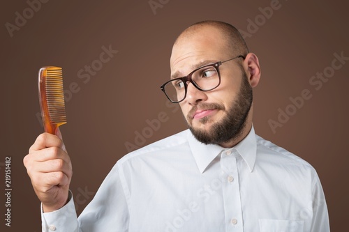 Adult bald man hand holding comb