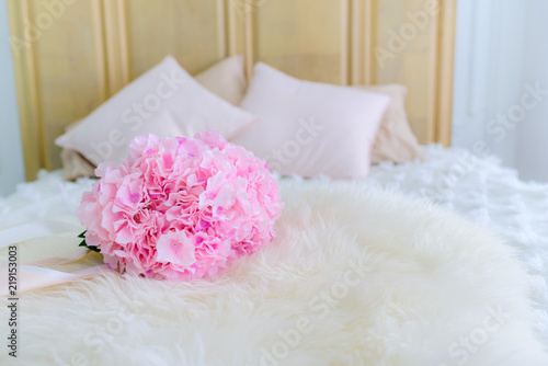 A pink flower bouquet is placed on the bed.