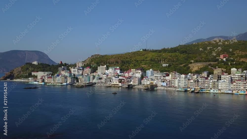 Aerial drone closing shot of colorful cityscape in the mountains over sea, Europe. Dense multi-storey building by the sea in the resort. Camera moves backwards. Crimea, Utes Ellings, Black Sea. Aerial drone closing shot of colorful cityscape in the mountains over sea, Europe. Dense multi-storey building by the sea in the resort. Camera moves backwards. Crimea, Utes Ellings, Black Sea.
