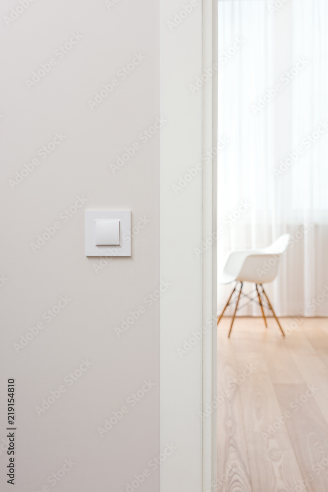 Naklejka premium Wall switch in light minimalist interior. Modern, beautiful, clean apartment in the background.