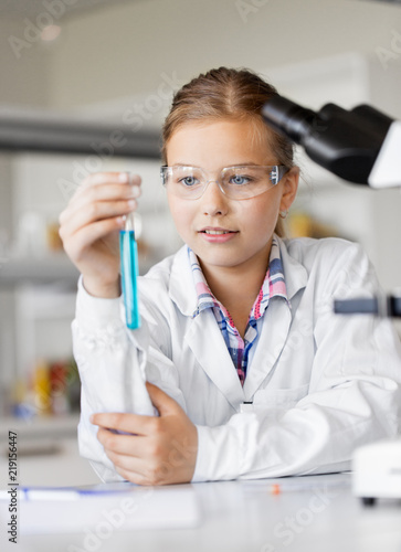 education  science and children concept - girl in goggles with test tube studying chemistry at school laboratory