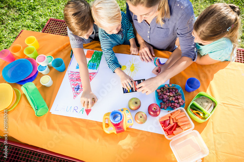 Schoolgirls and schoolboys painting during lunch break with fruits and sandwich photo