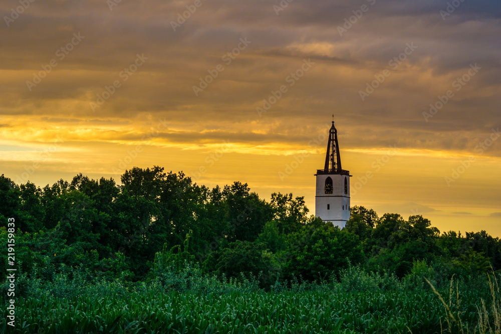 Germany, Church spire of denzlingen next to Freiburg orange twilight mood