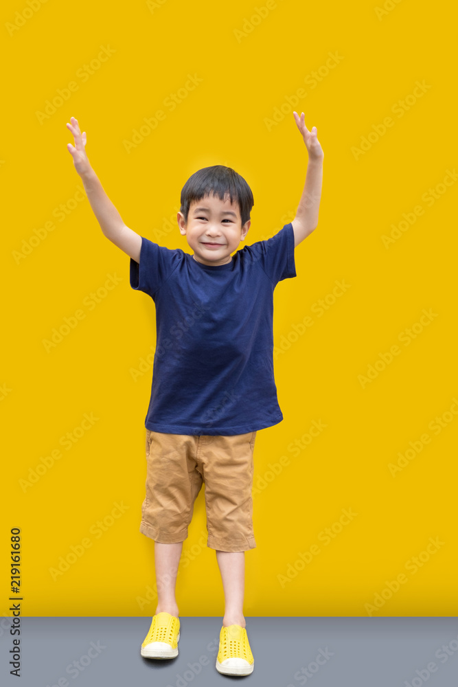 Asian Cute boy smile and stand with yellow wall background Asian Cute boy smile and stand with yellow wall background
