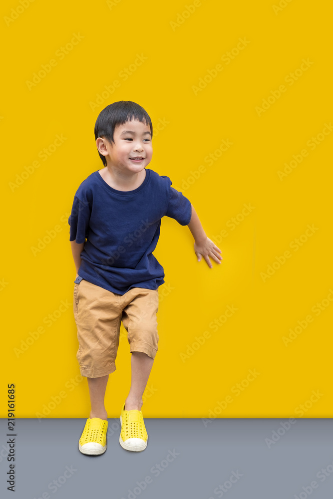 Asian Cute boy smile and stand with yellow wall background