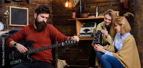 Man with long beard and stylish mustache relaxing with favorite instrument. Bearded man tuning electrical guitar, music and meditation concept. Hipster performing new song for his wife and daughter