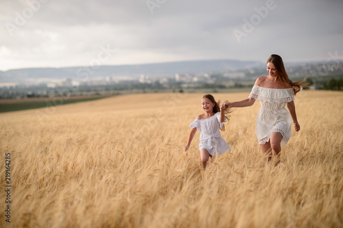 Beautiful family in a field of rye at sunset. A woman and child in amazing clothes walking through the field of rye.