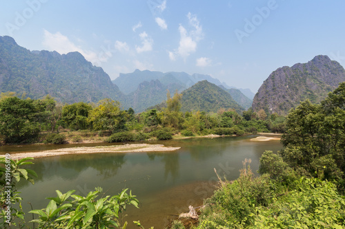 Beautiful view of the Nam Song River and karst limestone mountains near Vang Vieng, Vientiane Province, Laos, on a sunny day. © tuomaslehtinen
