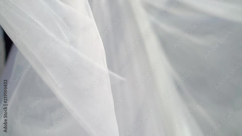 Bride and groom embracing in a city embankment, bride waving veil slowmotion at sunny day Bride and groom embracing in a city embankment, bride waving veil slowmotion at sunny day