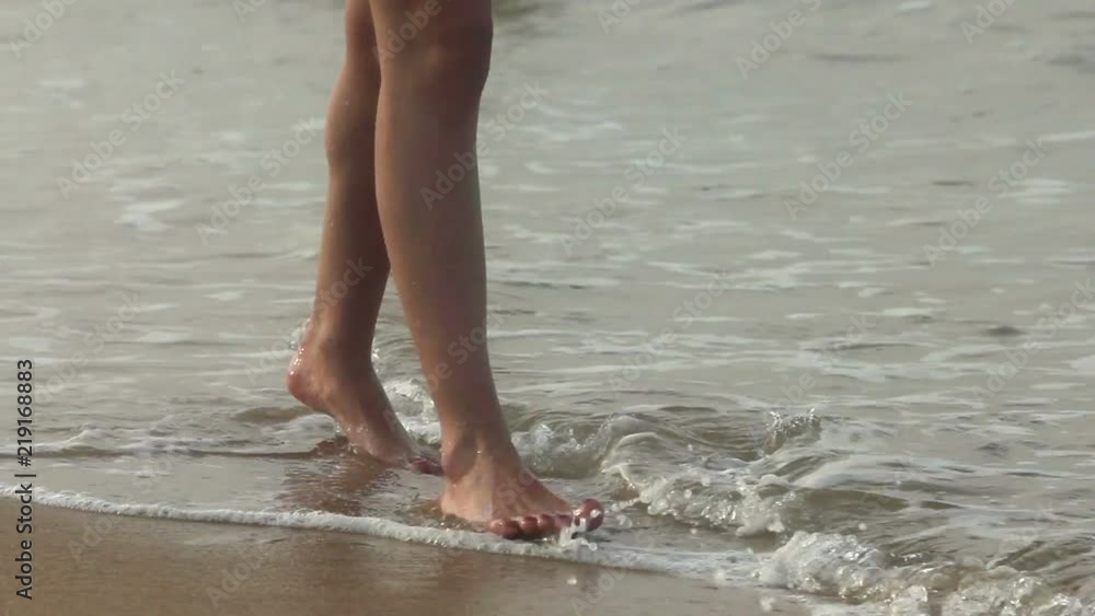 Bare feet walking on wet sand near the ocean Bare feet walking on wet sand near the ocean