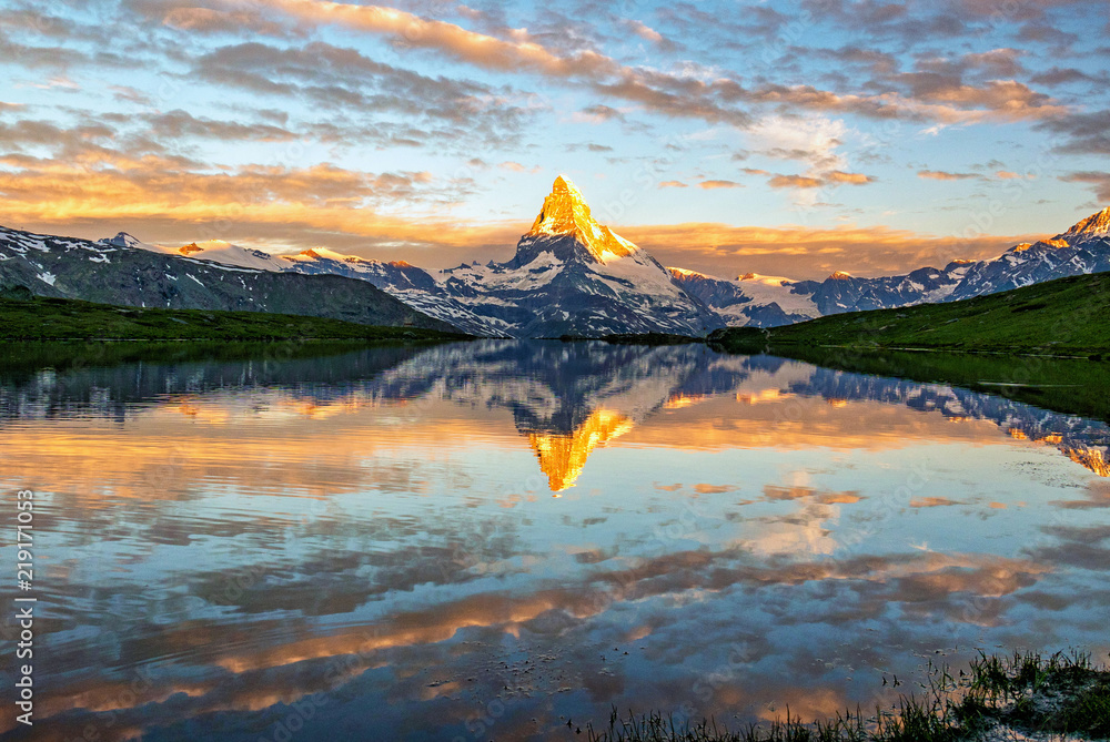 Obraz premium Morning shot of the golden Matterhorn (Monte Cervino, Mont Cervin) pyramid and blue Stellisee lake. Sunrise view of majestic mountain landscape.