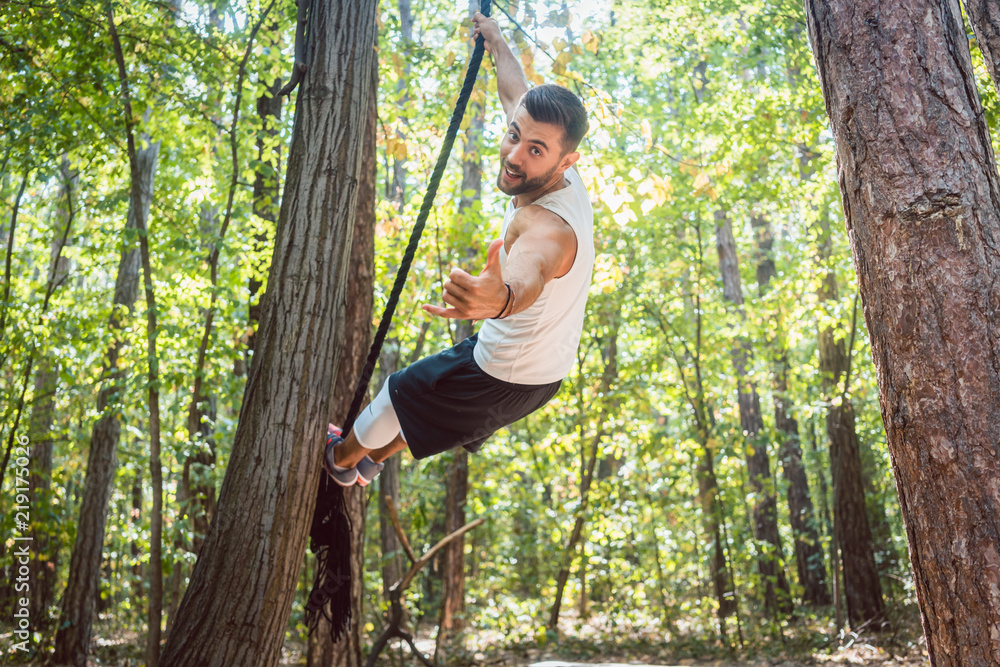 Muscular man having fun doing sport on the rope outdoors