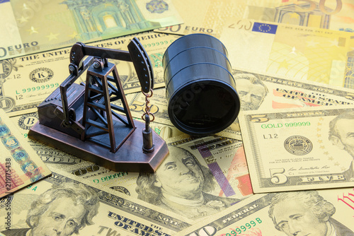 Petroleum, petrodollar and crude oil concept : Pump jack and a black barrel on US USD dollar notes, depicts the money received or earned from sales after investment in the development of oil industry. photo
