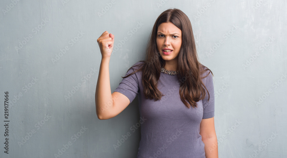 Young brunette woman over grunge grey wall annoyed and frustrated shouting with anger, crazy and yelling with raised hand, anger concept Young brunette woman over grunge grey wall annoyed and frustrated shouting with anger, crazy and yelling with raised hand, anger concept