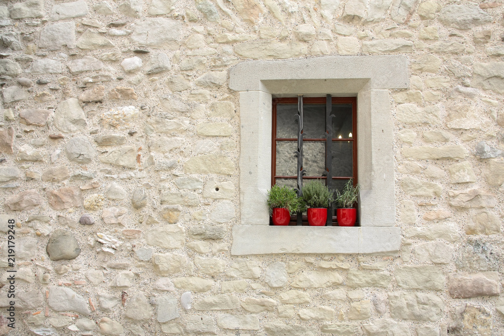 Stone window with spice plants in red pots