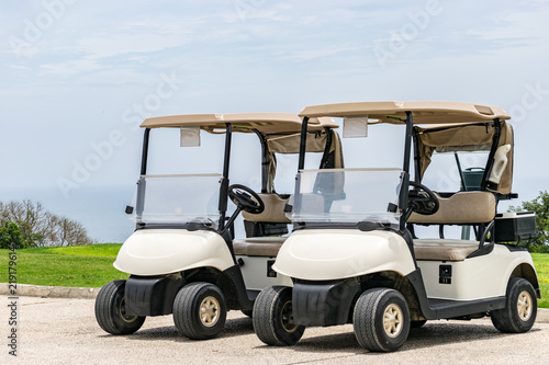Two empty white golf carts parked beside each other on the driveway of a golf course in Montego Bay, Jamaica.