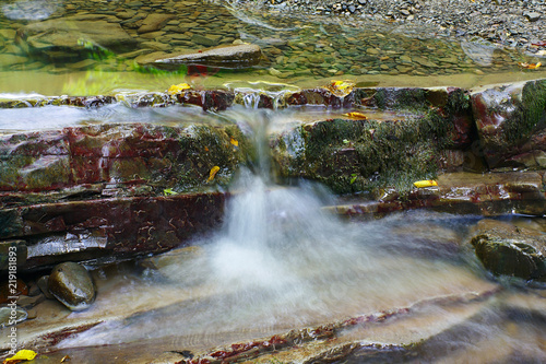 Refreshing stream of the mountain creek flows between the rocks