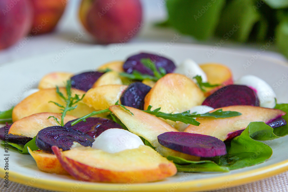 Delisious salad with peach, boiled beetroot, marinated mozzarella, arugula and olive oil.