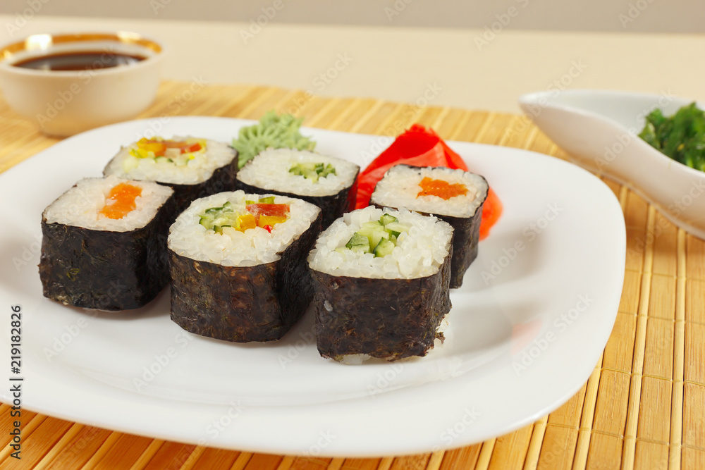 Sushi set, hiyashi wakame salad and soy sauce with ginger and wasabi on a bamboo mat close up. Sushi set, hiyashi wakame salad and soy sauce with ginger and wasabi on a bamboo mat close up.