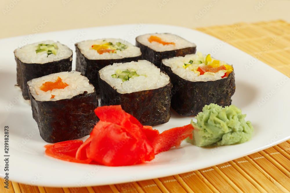 Sushi set with ginger and wasabi on a bamboo mat close up. Sushi set with ginger and wasabi on a bamboo mat close up.