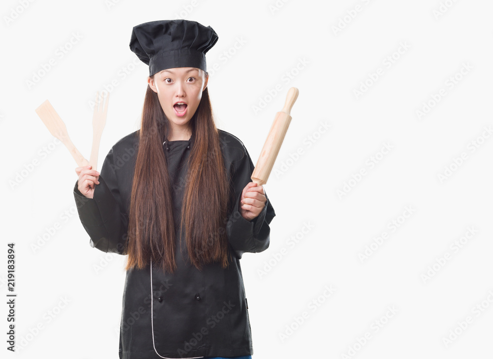 Young Chinese woman over isolated background wearing chef uniform scared in shock with a surprise face, afraid and excited with fear expression Young Chinese woman over isolated background wearing chef uniform scared in shock with a surprise face, afraid and excited with fear expression