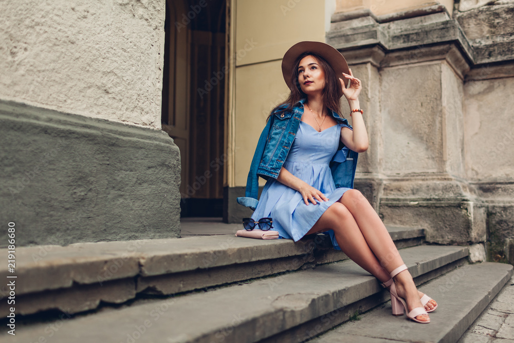 Outdoor portrait of young beautiful fashionable woman wearing stylish accessories. Girl sitting on stairs in city Outdoor portrait of young beautiful fashionable woman wearing stylish accessories. Girl sitting on stairs in city