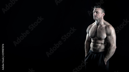 Bild auf Leinwand Man muscular torso body posing confidently black background, copy space