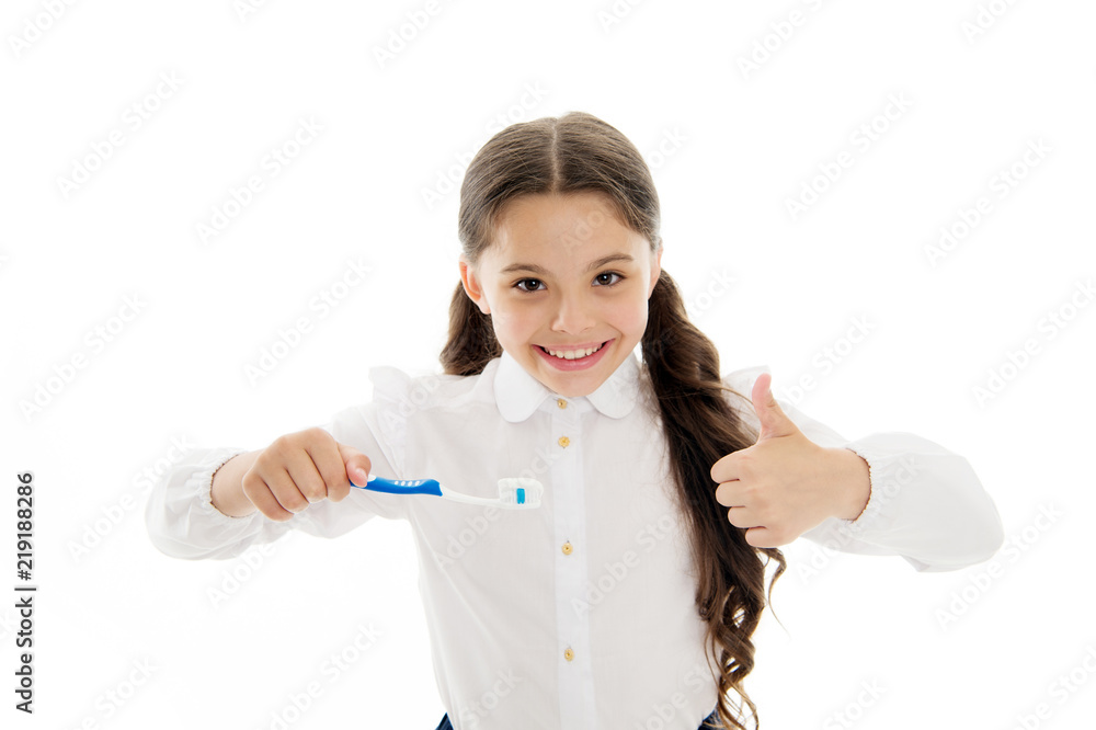Girl brilliant perfect smile holds toothbrush with drop of paste white background. Child holds toothbrush and shows thumbs up. Child schoolgirl happy face cares mouth hygiene. Brilliant smile concept Girl brilliant perfect smile holds toothbrush with drop of paste white background. Child holds toothbrush and shows thumbs up. Child schoolgirl happy face cares mouth hygiene. Brilliant smile concept